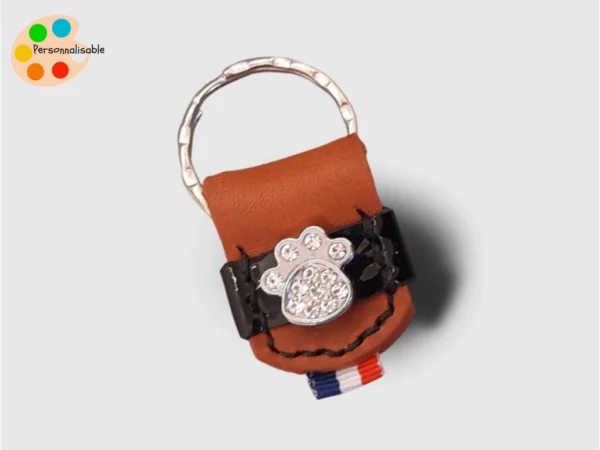 Un porte clé en cuir vernis avec une patte de chien à strass